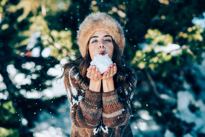 Portrait of woman holding snow standing outdoors