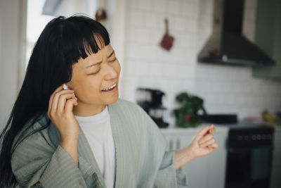 Cheerful young woman singing while listening music at home