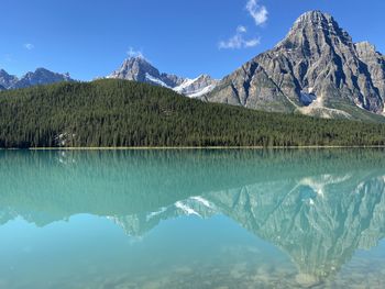 Scenic view of lake and mountains against blue sky