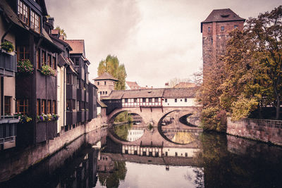 Bridge over river amidst buildings against sky