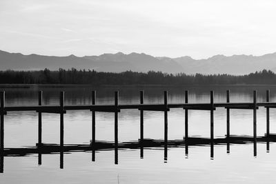 Reflection of pier in lake against sky