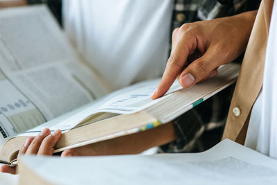 Midsection of students reading book