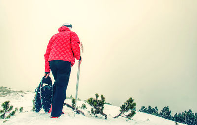 Man with snowshoe on snow path. man in snowshoes with trekking poles in snow in the mountains.