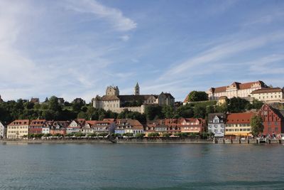 Buildings by river against sky