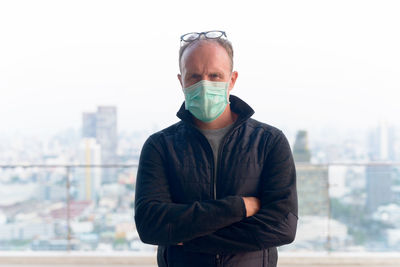 Portrait of mature man standing against cityscape