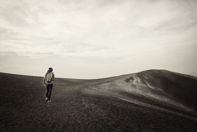 Rear view of man standing on land against sky