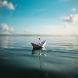 Close-up of paper boat floating on lake against sky