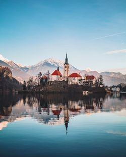 Buildings by lake against sky