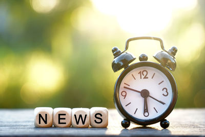 Close-up of clock and news text on table