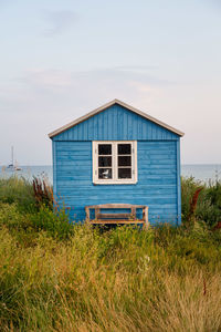 Beach hut on field against sky