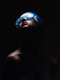 Close-up portrait of shirtless man against black background