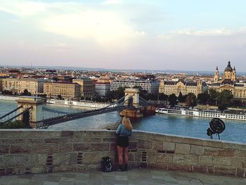 Rear view of woman looking at cityscape against sky