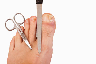 Close-up of hand holding metal against white background