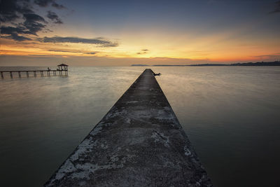 Old jetty over sea against sky during sunset at pasir panjang