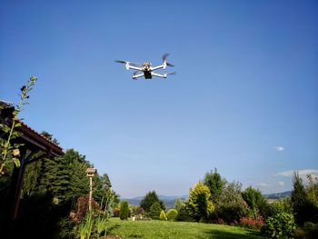 Low angle view of airplane flying against clear blue sky