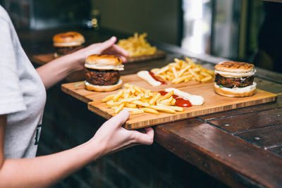 Cropped hands of woman holding food on tray