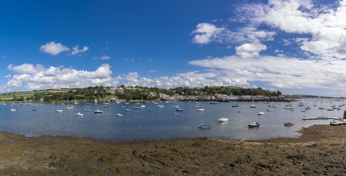 Boats moored on beach against blue sky