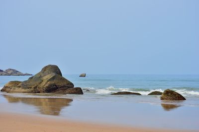 Rock formations on shore against clear sky