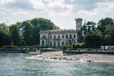 Buildings by river against sky