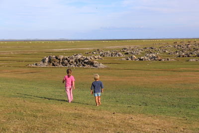 Rear view of people on field against sky