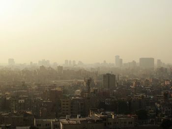 Aerial view of buildings in city against sky during foggy weather