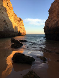 Rock formation on beach against sky during sunset