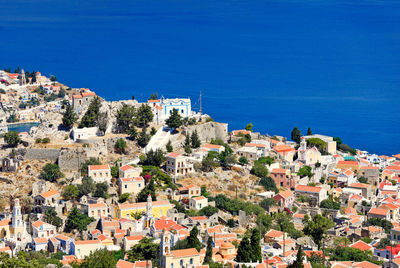 High angle view of townscape by sea against blue sky