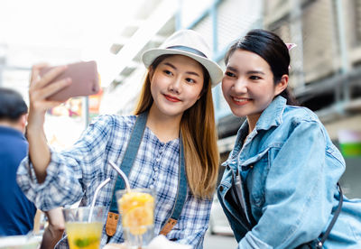 Portrait of smiling young couple holding smart phone outdoors