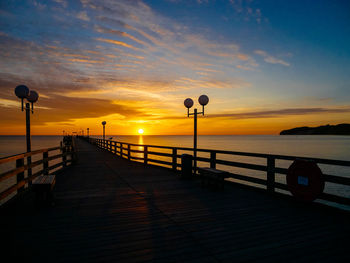 Street light by sea against sky during sunset