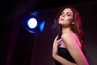 Portrait of young woman standing against black background