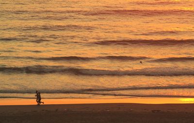 Man and woman jogging at beach during sunrise