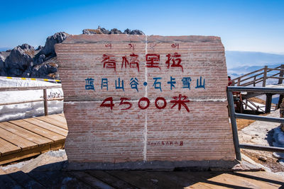 Text on wood against sky