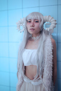 Portrait of young woman standing against wall