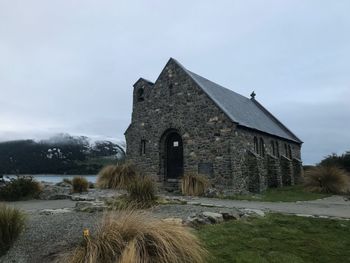 Old building on field against sky during winter