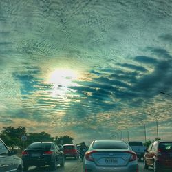 Cars on road against dramatic sky