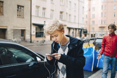 Man using mobile phone while standing on street in city