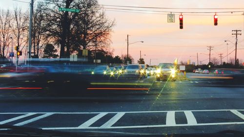 Cars on street against sky at sunset