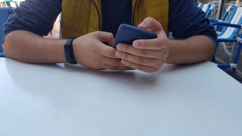 Midsection of man using mobile phone on table