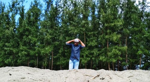 Man standing at beach against trees