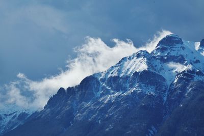 Low angle view of snowcapped mountains against blue sky