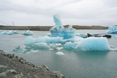 Ice floating on sea against sky during winter