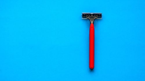 Close-up of red razor over blue background