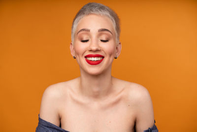 Close-up of happy young woman against orange background