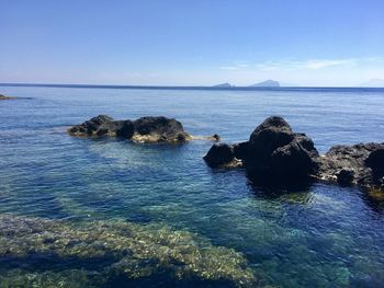 Scenic view of rocks in sea against blue sky