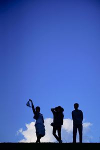Rear view of people standing against blue sky