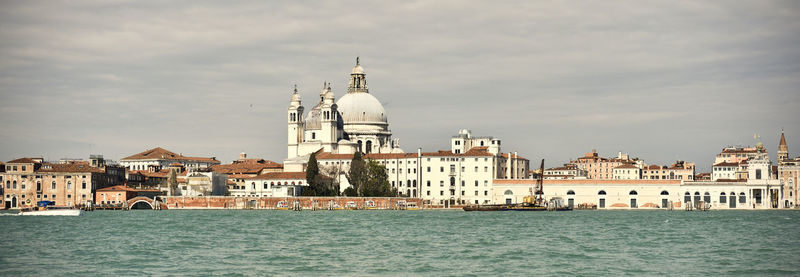 View of buildings by canal against sky