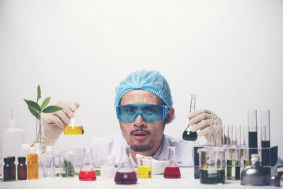 Portrait of scientist holding chemicals against white background