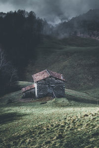 House on field by trees against sky