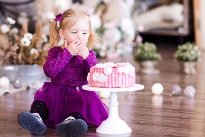 Cute girl sitting by cake at home
