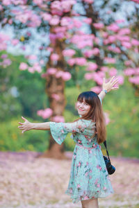 Full length of woman holding pink while standing outdoors